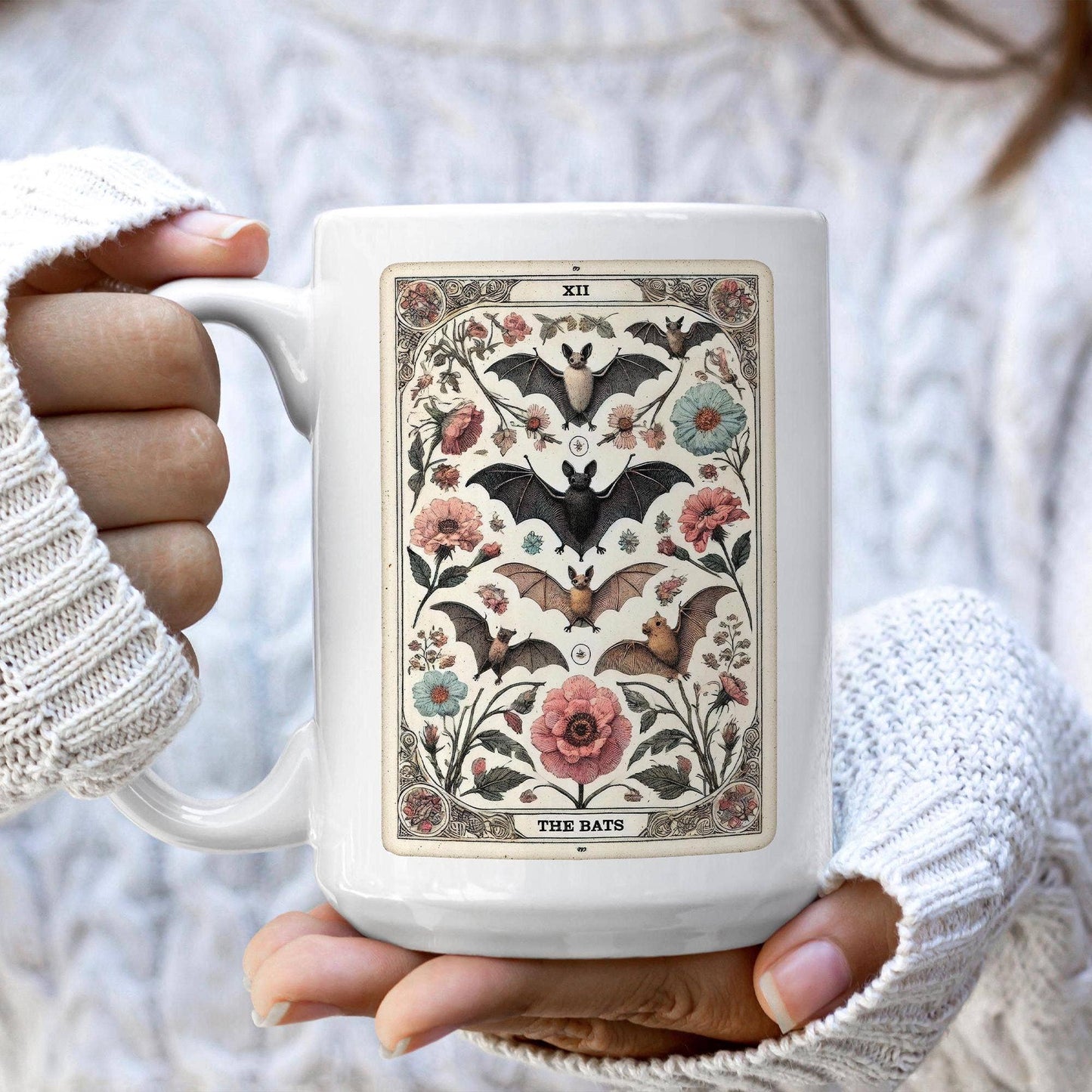 White mug with a decorative design featuring bats and flowers held by a person wearing white gloves.