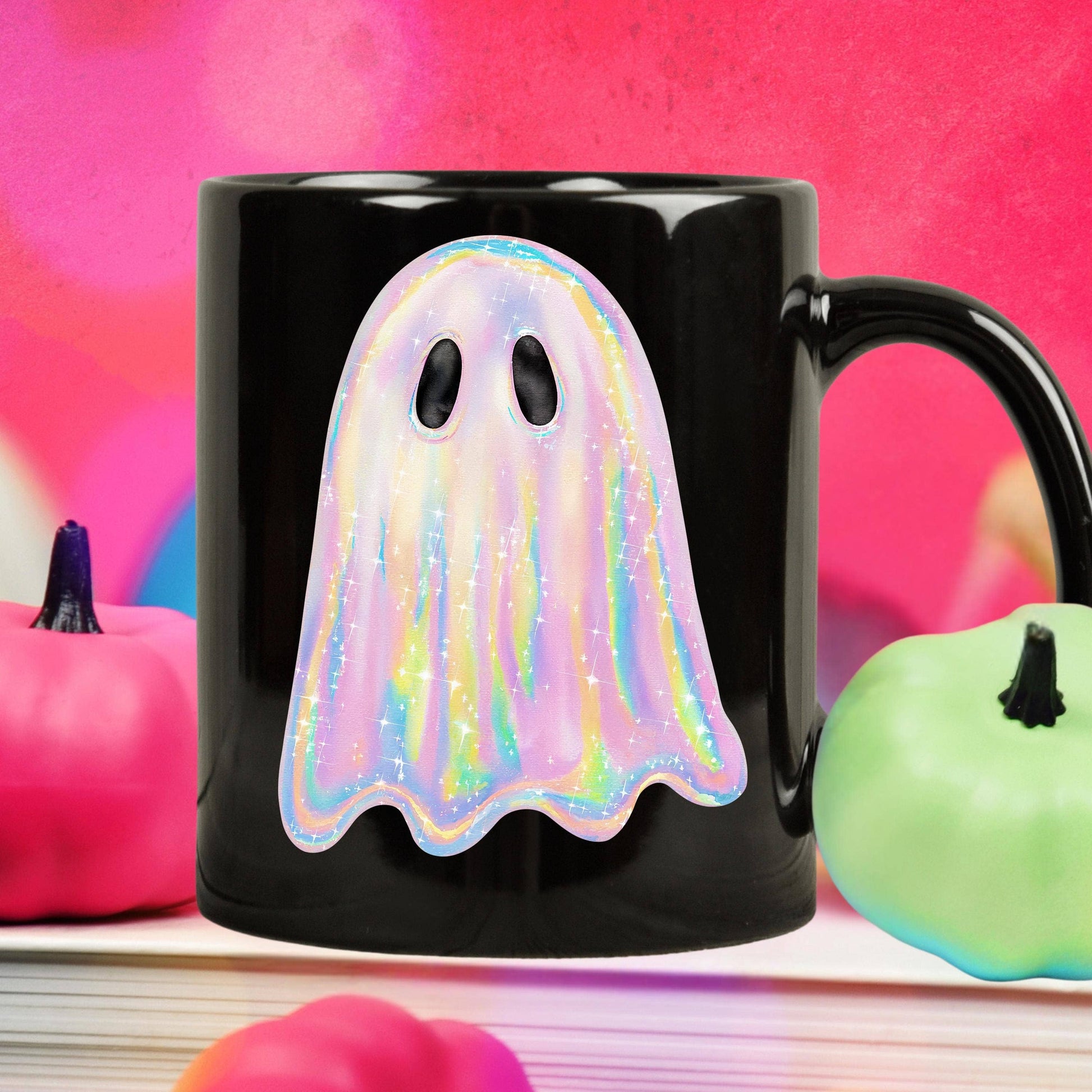 Black mug with a colorful ghost design on a pink and orange background with pumpkins.