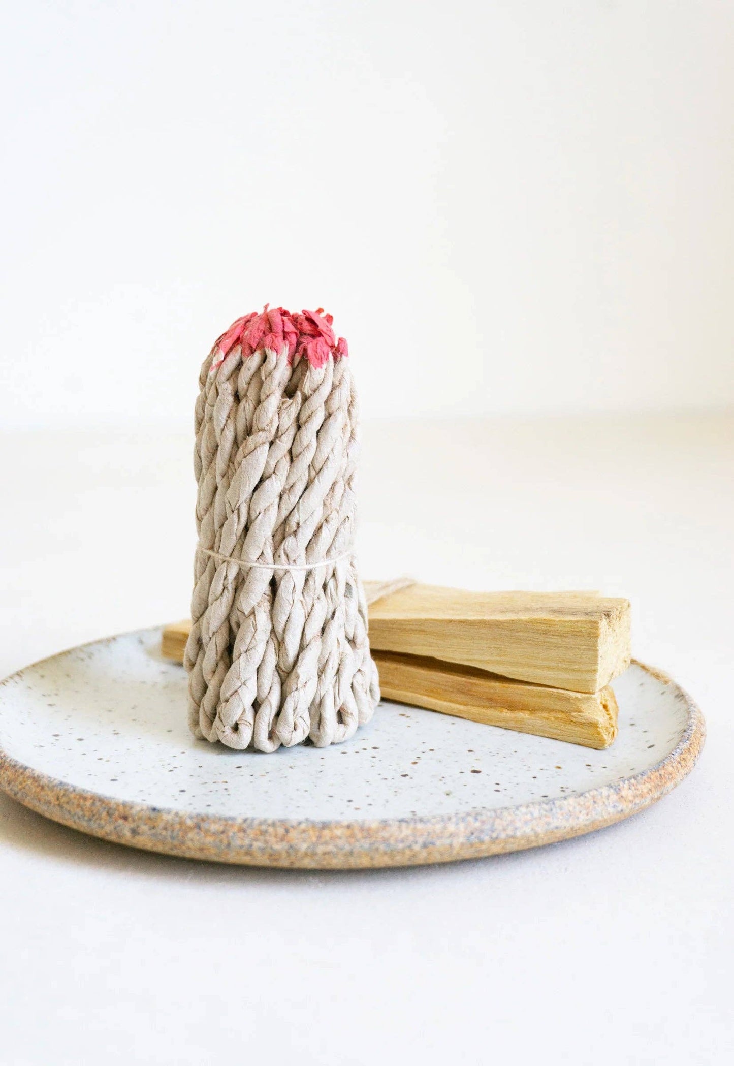 rope incense with red tips on a ceramic plate against a white background