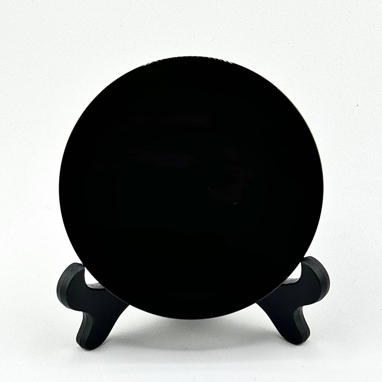 Black scrying mirror on a stand against a white background