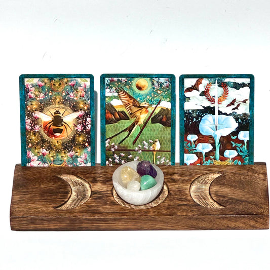 Three tarot cards on a wooden stand with decorative elements