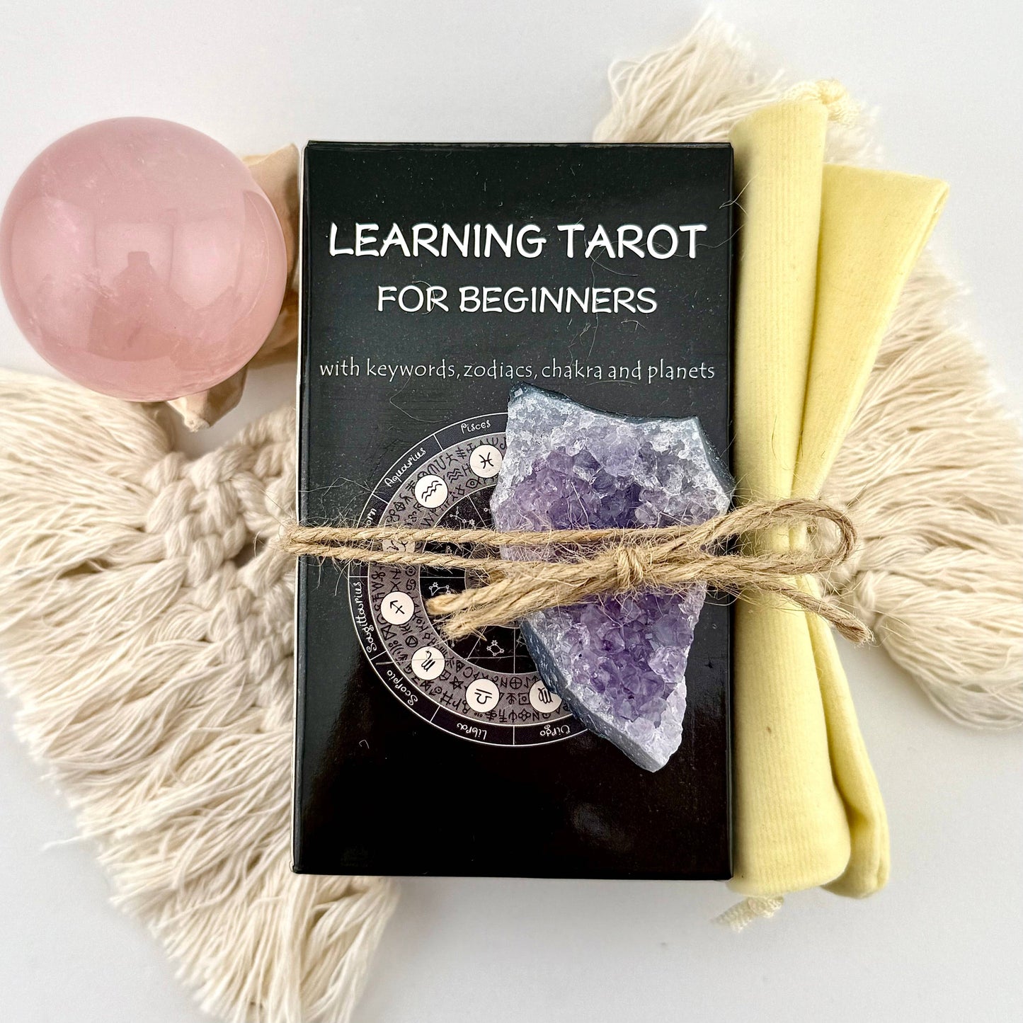 Learning Tarot for Beginners book with amethyst crystal, pink crystal ball, and yellow cloth on a white background