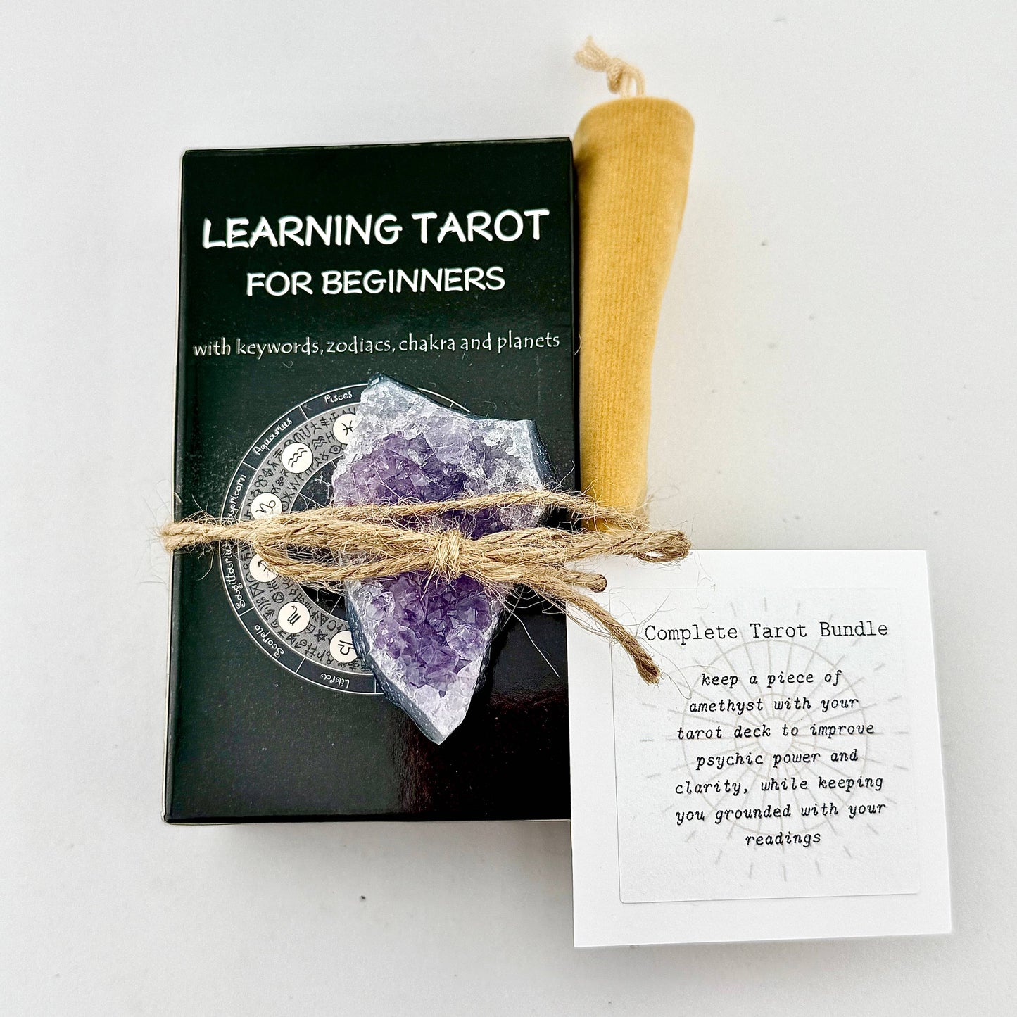 Tarot bundle with book, amethyst crystal, and candle on a white background